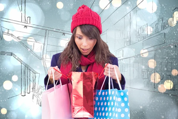 Shocked brunette opening gift bag — Stock Photo, Image