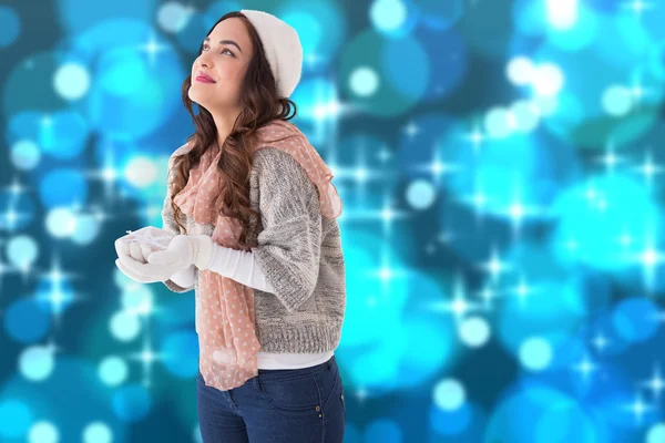 Kompositbild einer Brünetten in Winterkleidung mit ausgestreckten Händen — Stockfoto