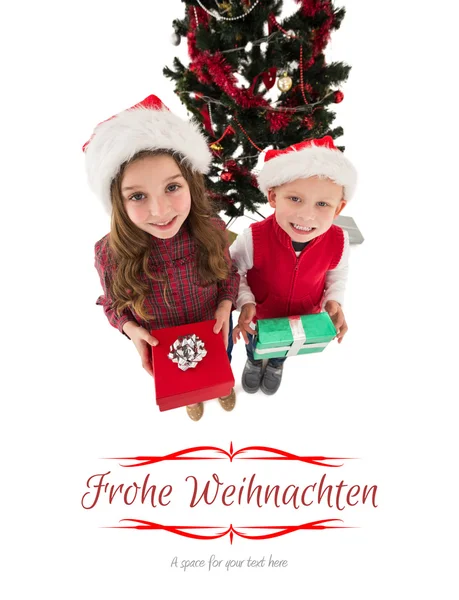 Composite image of festive little siblings smiling at camera hol — Stock Photo, Image