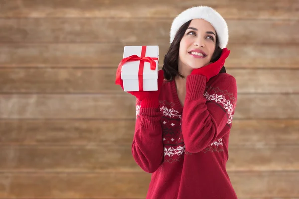 Zusammengesetztes Bild einer überraschten Brünetten mit Weihnachtsmann-Hut und Geschenk — Stockfoto