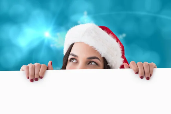 Composite image of pretty brunette in santa hat showing white po — Stock Photo, Image