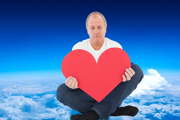 Rozrušený muž sedí, drží tvar srdce — Stock fotografie
