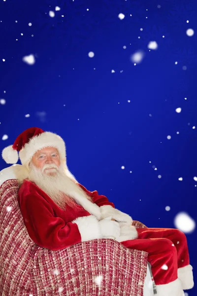 Smiling santa relaxing on chair — стоковое фото