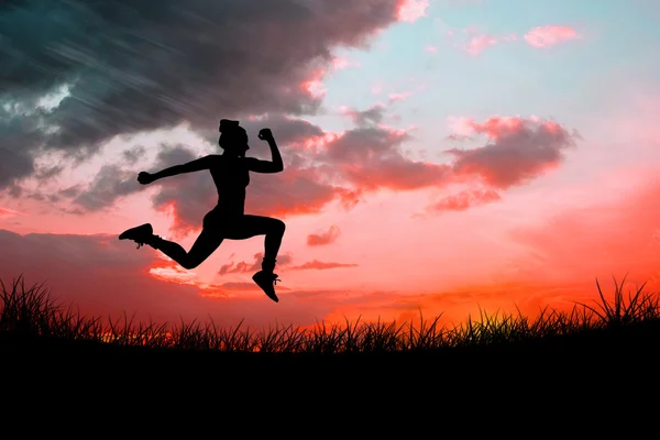 Fitte Brünette läuft gegen den roten Himmel — Stockfoto