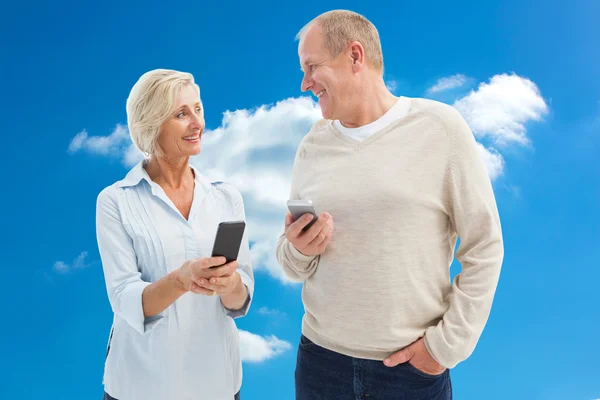 Pareja madura feliz usando sus teléfonos inteligentes — Foto de Stock