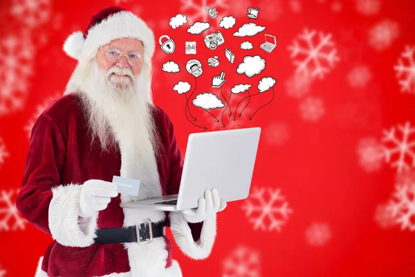 Санта платит кредитной картой на ноутбуке — стоковое фото