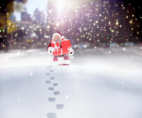 Santa uitvoering van geschenken in de sneeuw — Stockfoto