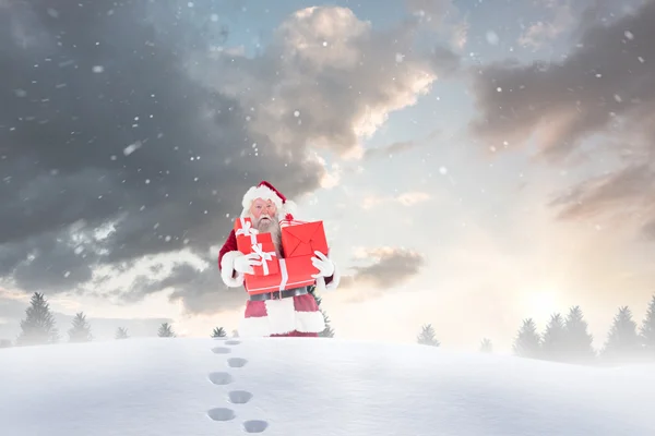 Santa carrying gifts in snow — Stock Photo, Image