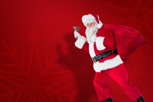 Imagem composta de Papai Noel andando com seu saco e sino — Fotografia de Stock