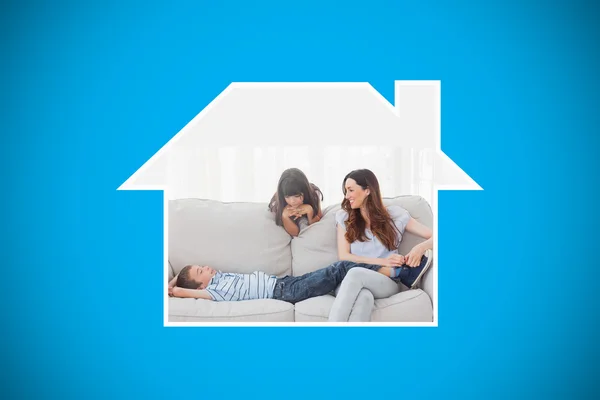 Moeder zit met haar kinderen op sofa — Stockfoto