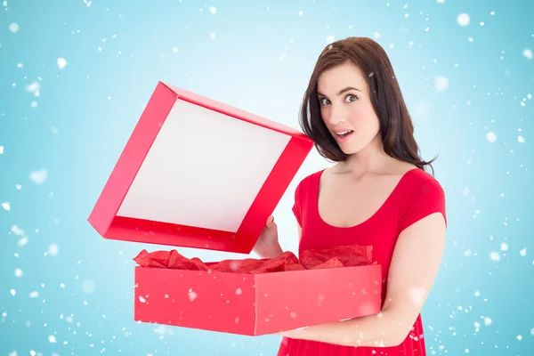 Brunette in red dress opening gift — Stock Photo, Image
