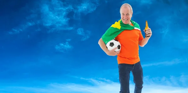 Reifer Mann im orangefarbenen T-Shirt hält Fußball in der Hand — Stockfoto