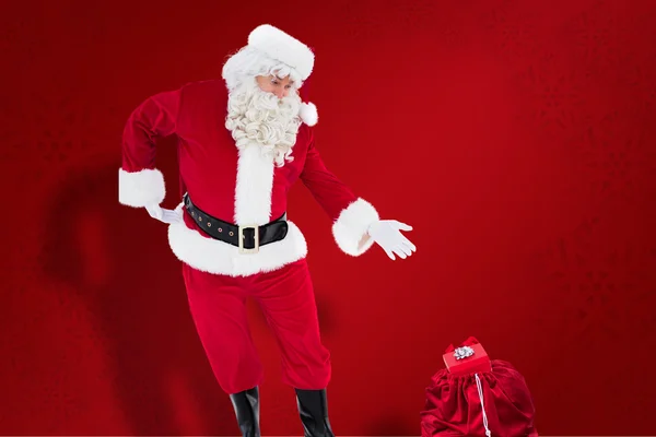 Composite image of santa claus showing sack full of gifts — Stock Photo, Image