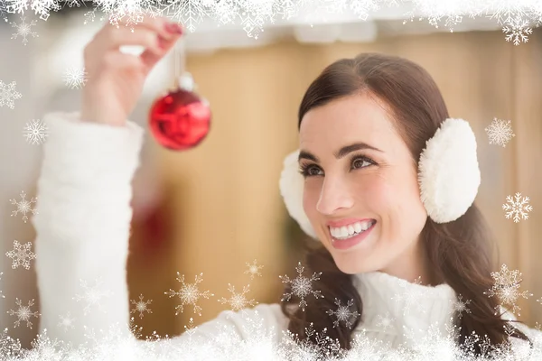 Sonriente morena sosteniendo una chuchería en Navidad — Foto de Stock