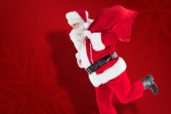 Composite image of santa claus walking with a sack — Stock Photo, Image