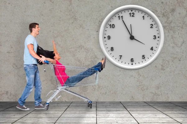 Composite image of young couple having fun with shopping cart — Stock Photo, Image