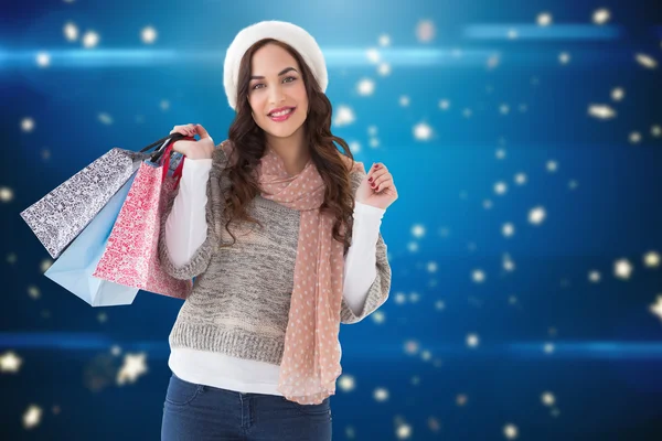 Imagen compuesta de cabello castaño en ropa de invierno sosteniendo compras — Foto de Stock