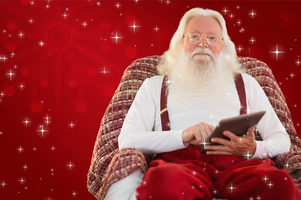 Santa za pomocą tabletu na fotel — Zdjęcie stockowe
