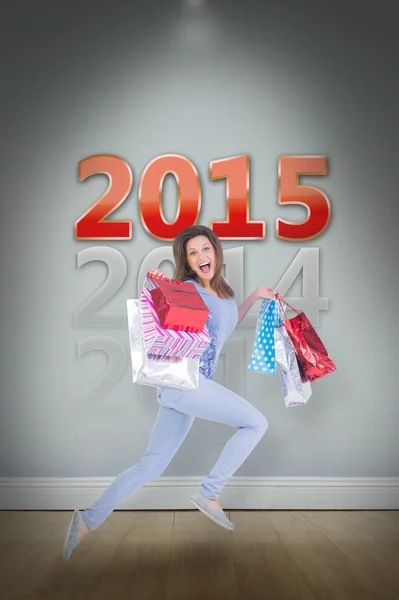 Smiling brunette jumping while holding shoppig — Stock Photo, Image