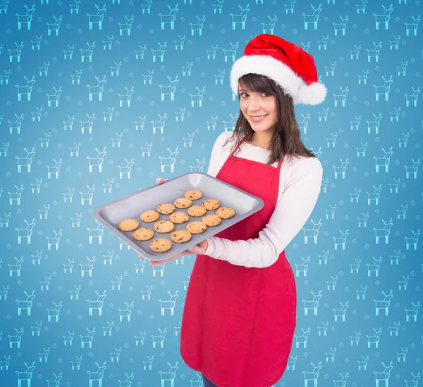 Brunette in santa hat offering hot cookies — Stock Photo, Image