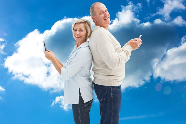 Pareja madura feliz usando sus teléfonos inteligentes —  Fotos de Stock