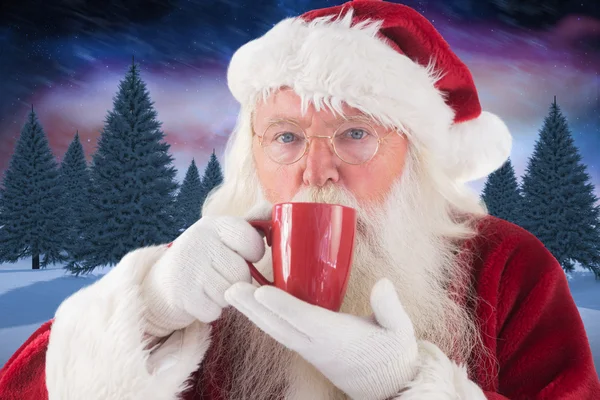 Weihnachtsmann trinkt aus roter Tasse — Stockfoto