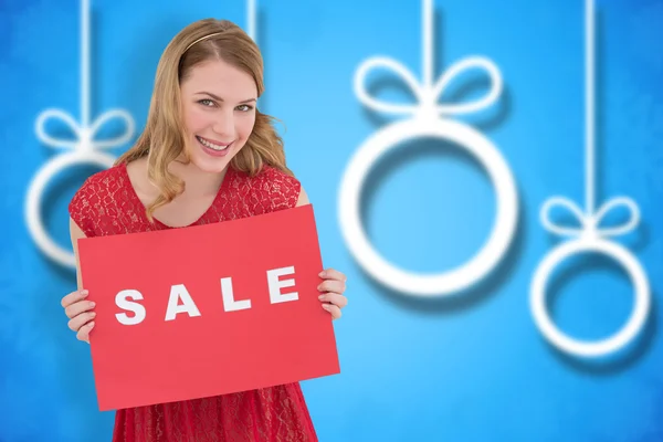 Rubia sonriente mostrando un cartel de venta roja — Foto de Stock
