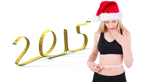 Composite image of fit festive young blonde looking at measuring — Stock Photo, Image