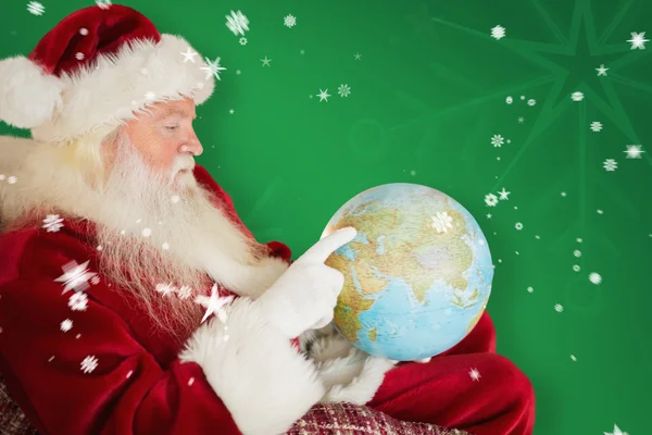 Santa Claus pointing to globe — Stock Photo, Image