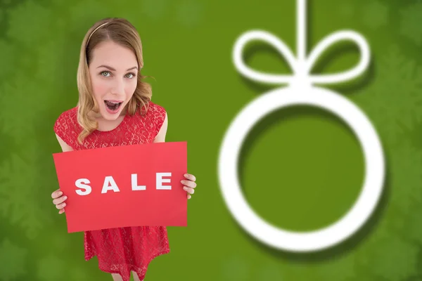 Surprised blonde showing a red sale poster — Stock Photo, Image
