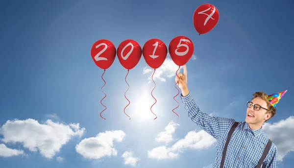 Hipster in feest hoed wijzend op ballonnen — Stockfoto