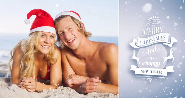 Pareja acostada en la playa con sombreros de navidad —  Fotos de Stock