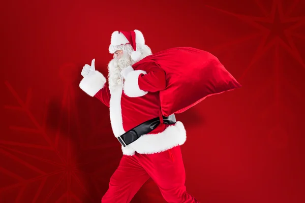 Papai Noel positivo com um saco e polegares para cima — Fotografia de Stock