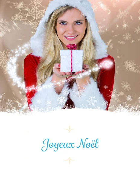 Composite image of pretty girl in santa outfit holding gift — Stock Photo, Image