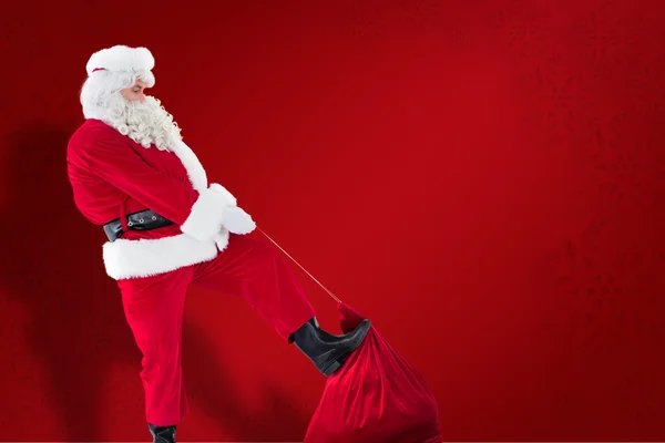 Composite image of santa claus clothing his sack — Stock Photo, Image