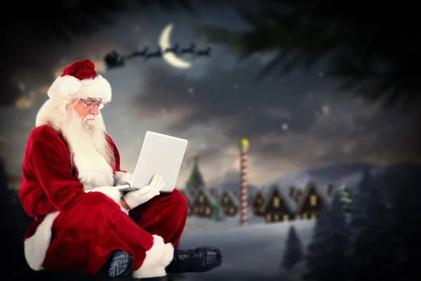 Santa sits and uses laptop — Stock Photo, Image