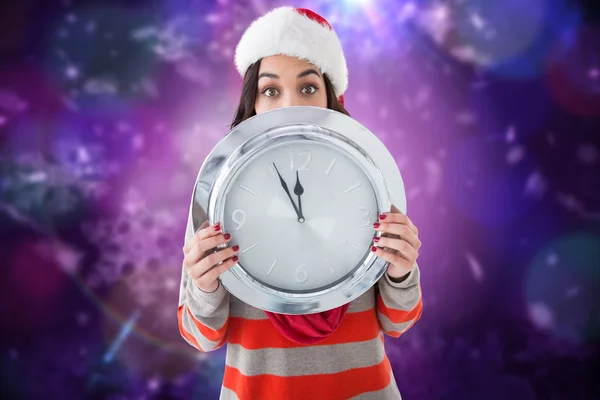 Imagen compuesta de morena festiva sosteniendo un reloj — Foto de Stock