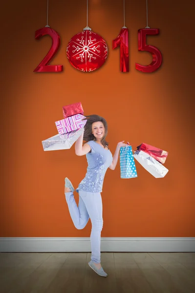 Smiling brunette jumping while holding shoppig — Stock Photo, Image