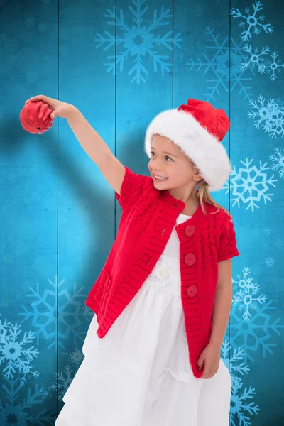 Zusammengesetzte Bild von niedlichen kleinen Mädchen mit Weihnachtsmütze hält ba — Stockfoto