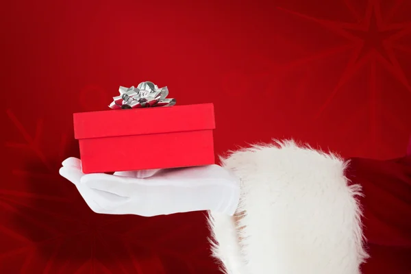 Composite image of hand of santa claus holding a gift — Stock Photo, Image