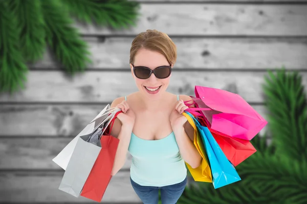 Imagem composta de mulher segurando sacos de compras usando sunglasse — Fotografia de Stock