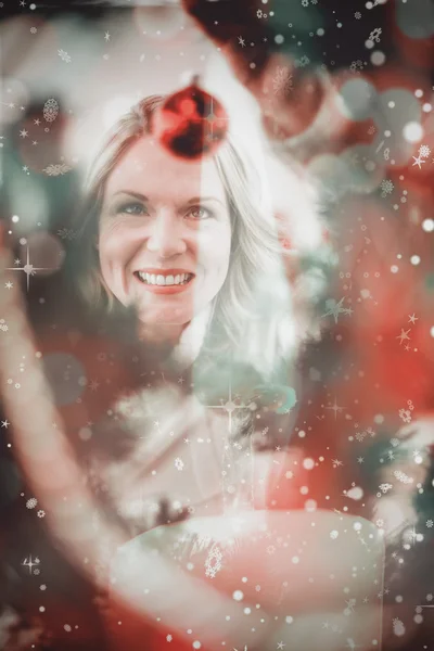 Festliche Blondine hängt Christbaumkugel an Weihnachten — Stockfoto