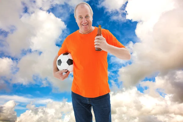 Reifer Mann im orangefarbenen T-Shirt hält Fußball in der Hand — Stockfoto