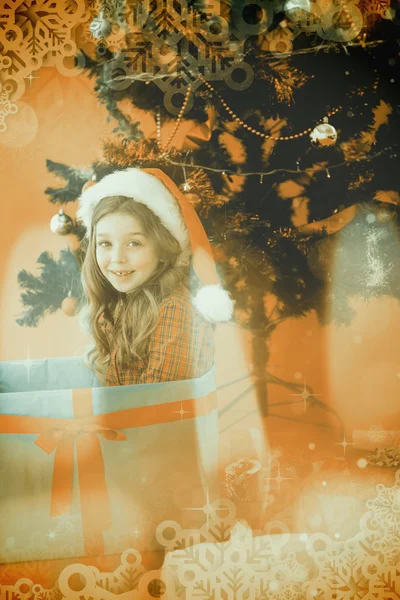 Imagen compuesta de la niñita festiva sentada en un gran regalo — Foto de Stock