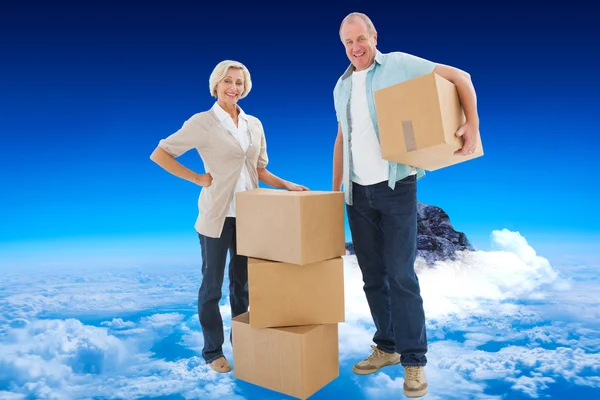 Older couple smiling at camera with moving box — Stock Photo, Image