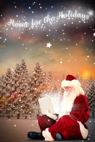 Santa sedí a používá notebook — Stock fotografie