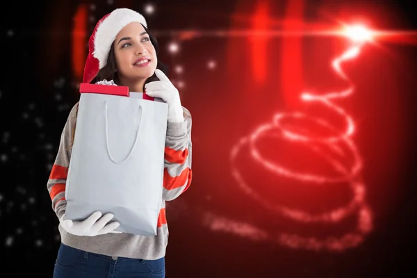 Composite image of thoughtful brunette holding shopping bag full — Stock Photo, Image