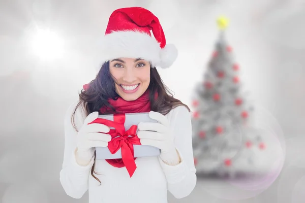 Festlig brunett i santa hatt hålla gåva — Stockfoto