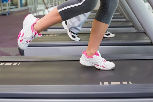 Unterteil eines Paares, das im Fitnessstudio auf Laufbändern läuft — Stockfoto