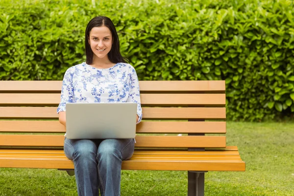 Brune joyeuse assise sur un banc à l'aide d'un ordinateur portable — Photo